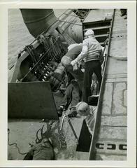Photograph, Sailors aboard the U.S.S. Rudyerd Bay tending to a seaman injured in the crash of an FM2 aircraft.