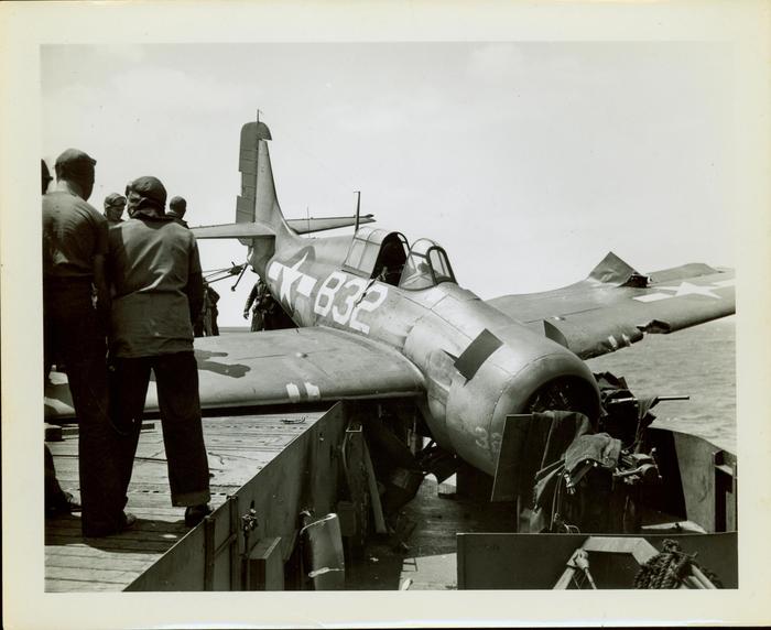 Photograph, Sailors aboard U.S.S. Rudyerd Bay looking at crashed FM2 aircraft on the portside catwalk.