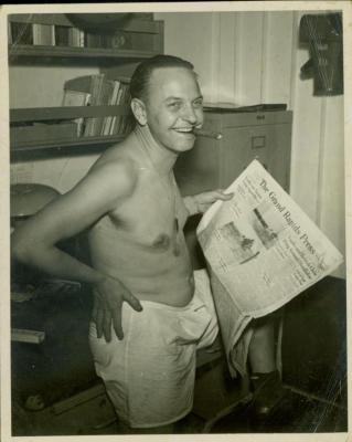 Photograph,  Aurey Strohpaul holding his hometown newspaper, The Grand Rapids Press while aboard the U.S.S. Rudyerd Bay.